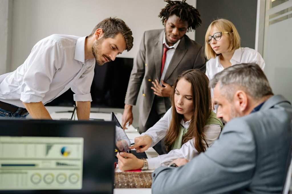 A diverse team engages in a collaborative meeting in a modern office setting, focused on digital analysis.